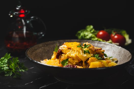Plat de pâtes au poulet et légumes, décoré de persil frais, avec une carafe de boisson et des tomates en arrière-plan.